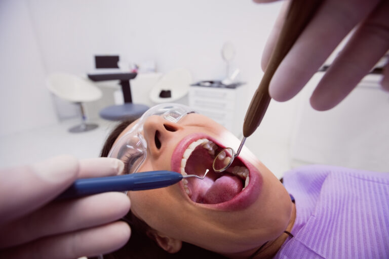 Dentist examining a female patient with tools at dental clinic